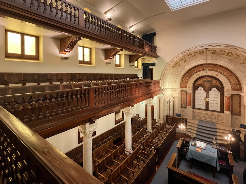 Interior of Shaare Tikvah Synagogue in Lisbon with ornate ark, Hebrew inscriptions, and wooden gallery, featured on a Jewish heritage tour in Portugal.